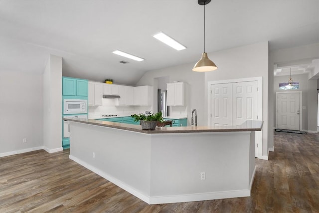 kitchen with white microwave, a spacious island, under cabinet range hood, white cabinets, and dark wood-style flooring