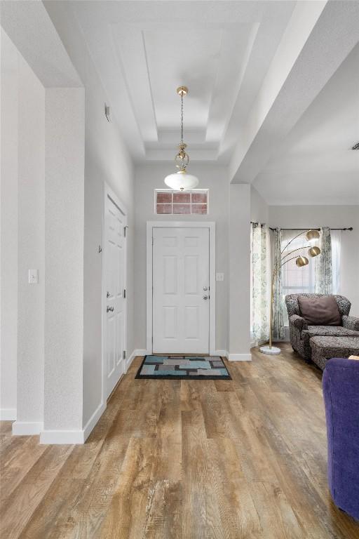 entrance foyer featuring baseboards, a tray ceiling, and wood finished floors