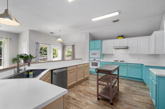 kitchen featuring visible vents, a sink, under cabinet range hood, white appliances, and light wood finished floors