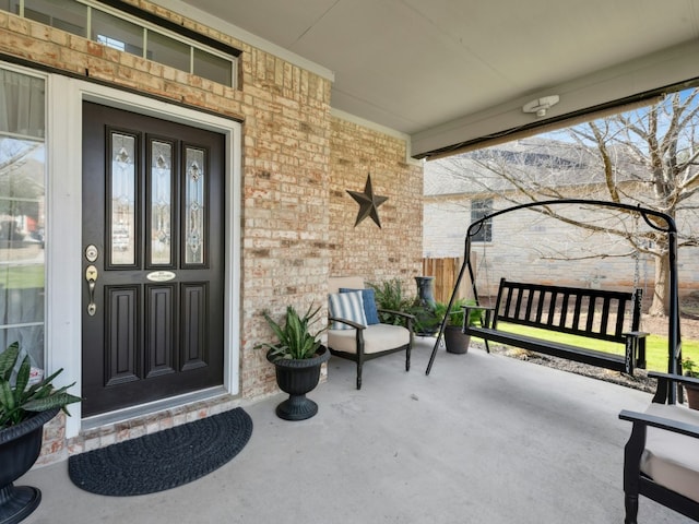 entrance to property with a porch and brick siding