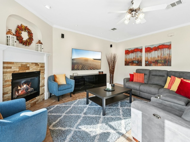 living room featuring visible vents, a stone fireplace, and ornamental molding