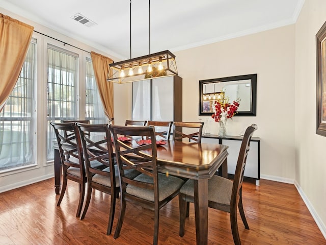 dining room with visible vents, ornamental molding, and wood finished floors