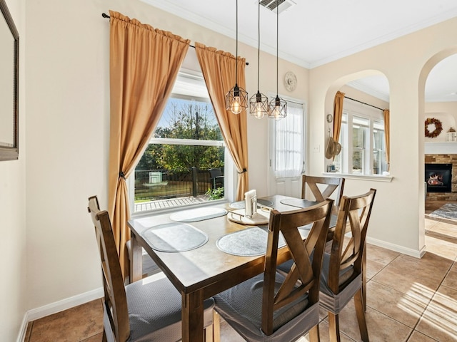 dining room with light tile patterned floors, a fireplace, crown molding, and baseboards