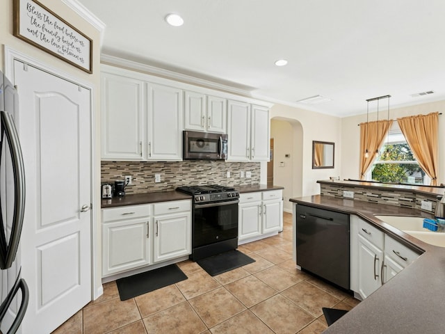 kitchen with arched walkways, a sink, stainless steel appliances, white cabinetry, and dark countertops