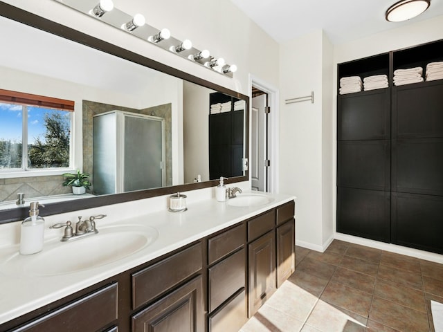 full bath featuring a sink, double vanity, a shower stall, and tile patterned floors