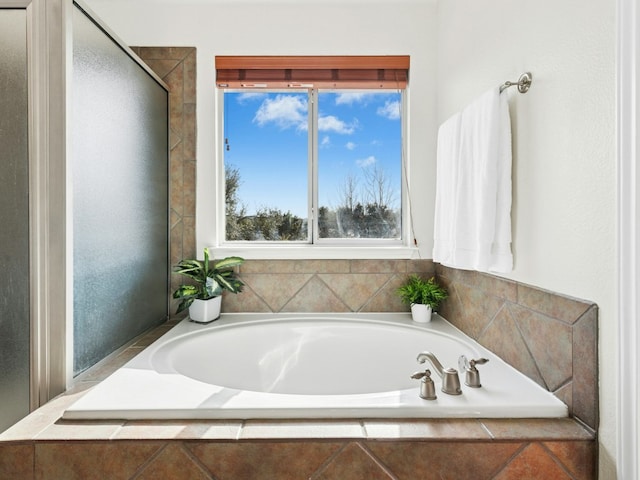 bathroom featuring a garden tub and a shower with shower door