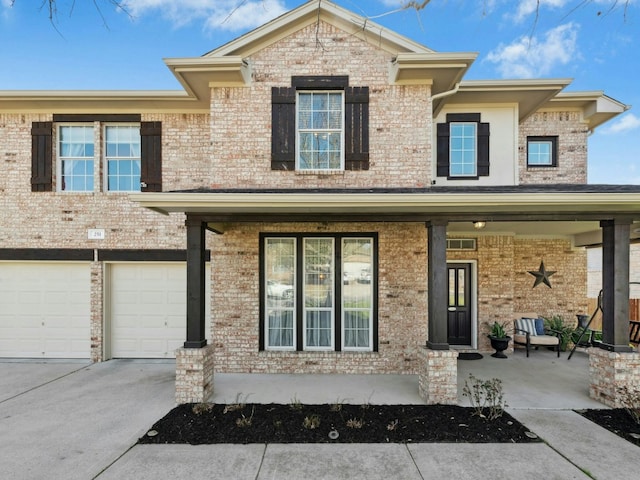 townhome / multi-family property with brick siding, a porch, and concrete driveway