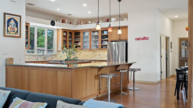 kitchen with visible vents, backsplash, freestanding refrigerator, glass insert cabinets, and light stone countertops