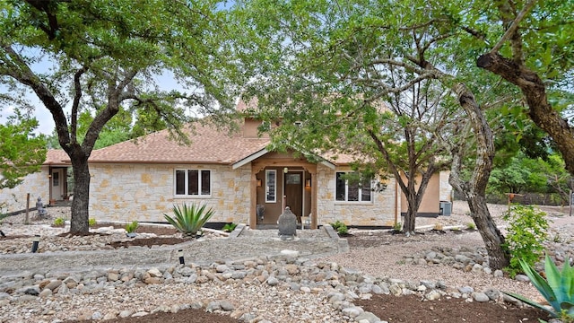 view of front of property with stone siding and roof with shingles