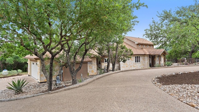 view of front of property with concrete driveway, a garage, and stone siding