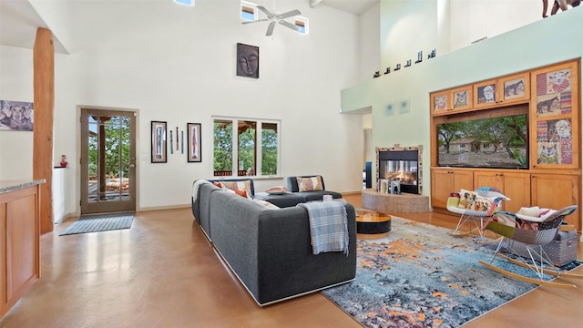 living room with a tiled fireplace, a high ceiling, baseboards, and concrete flooring