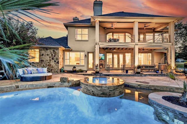 back of house featuring a patio, a balcony, a chimney, stucco siding, and french doors