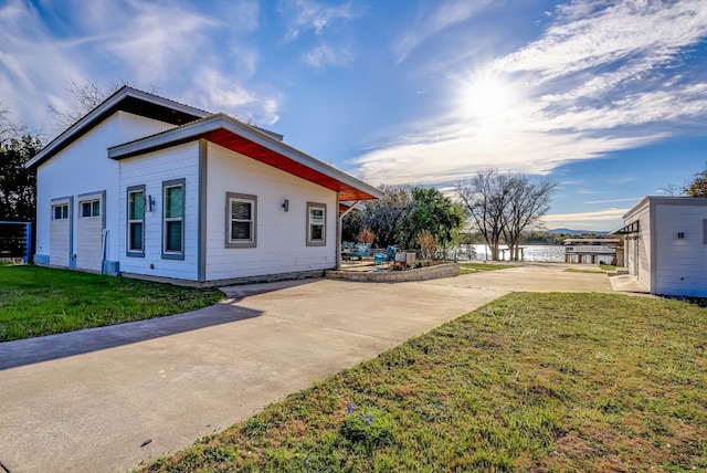 view of property exterior featuring a water view, a lawn, and a patio area