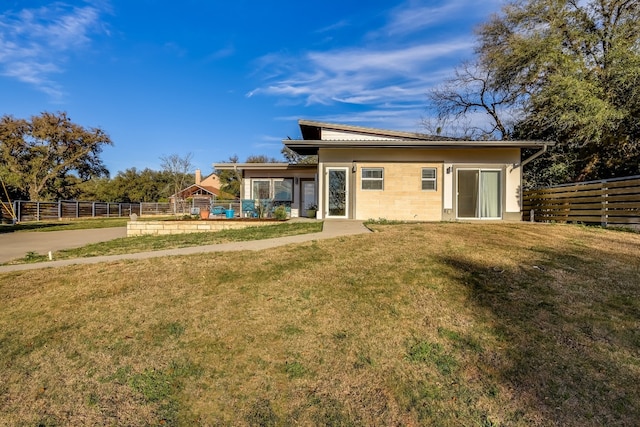 back of property featuring a lawn and fence