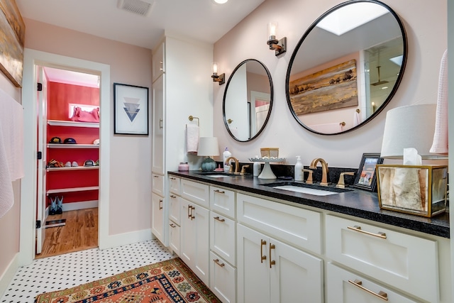 bathroom with double vanity, baseboards, visible vents, and a sink