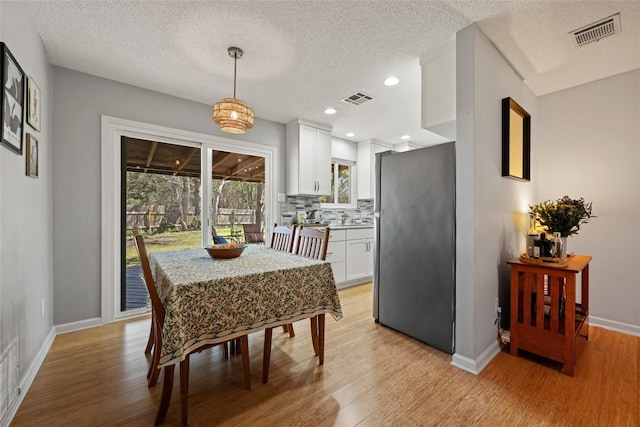 dining space with visible vents, baseboards, and light wood-style floors