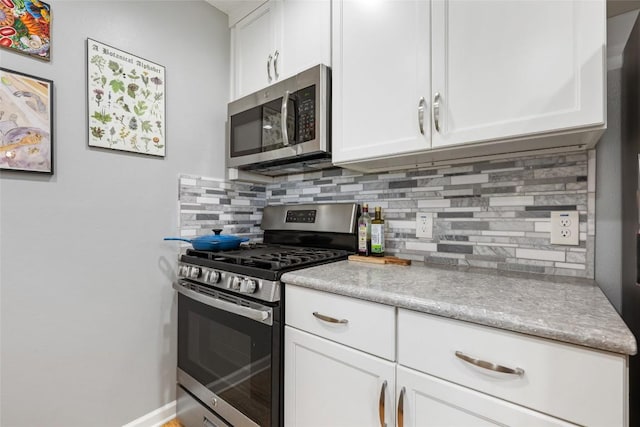 kitchen featuring baseboards, light countertops, appliances with stainless steel finishes, white cabinetry, and backsplash