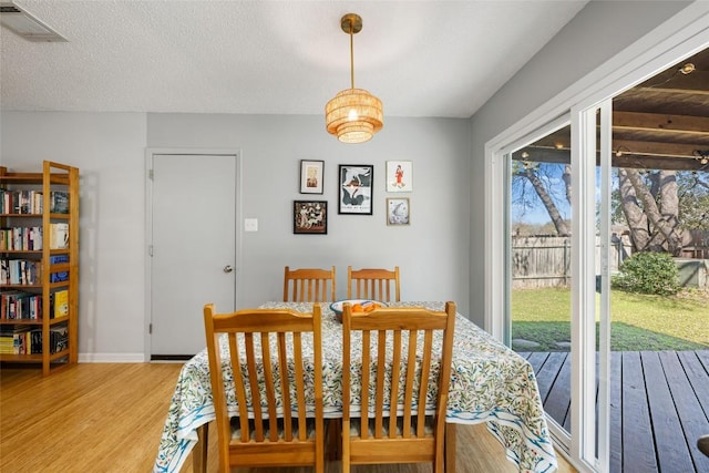 dining space featuring visible vents, baseboards, a textured ceiling, and wood finished floors