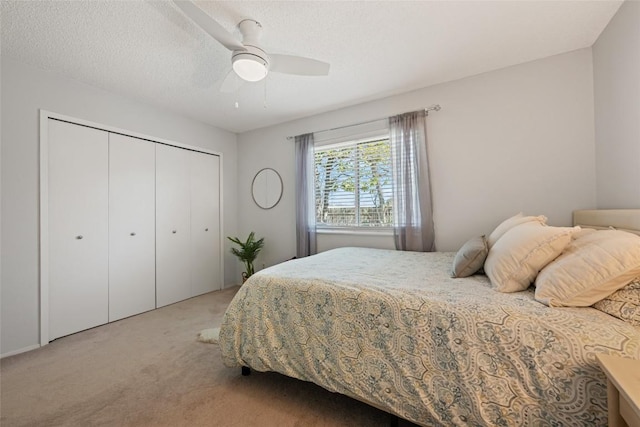 bedroom with a textured ceiling, a ceiling fan, a closet, and light carpet