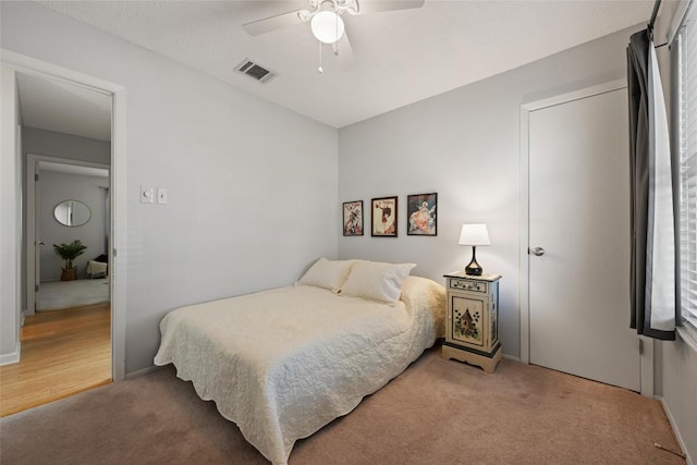 bedroom featuring visible vents, light carpet, and a ceiling fan