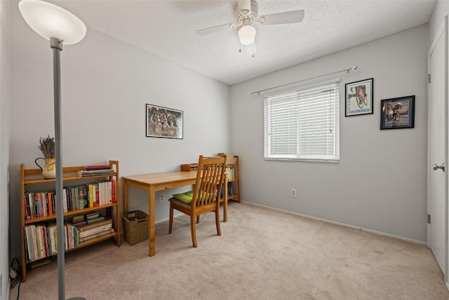 carpeted office space featuring baseboards, a textured ceiling, and ceiling fan