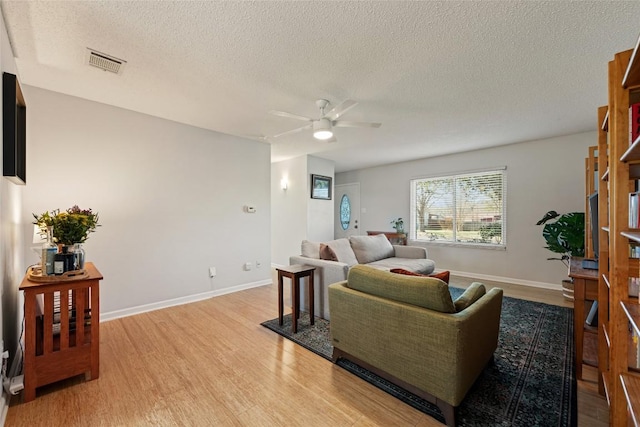 living room featuring visible vents, light wood-style flooring, baseboards, and a ceiling fan