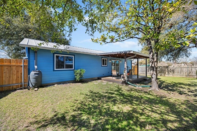 back of house with a patio area, a lawn, a fenced backyard, and metal roof