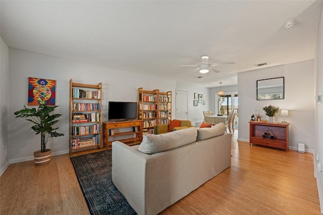 living area featuring baseboards, visible vents, and light wood-type flooring