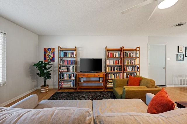 living room featuring a wealth of natural light, visible vents, a textured ceiling, and wood finished floors