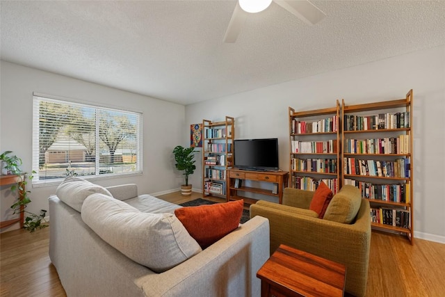 living room featuring baseboards, a textured ceiling, wood finished floors, and a ceiling fan