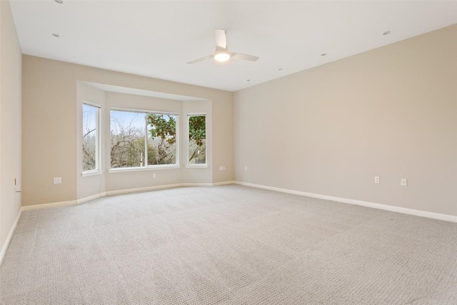 unfurnished room featuring baseboards, light carpet, and a ceiling fan