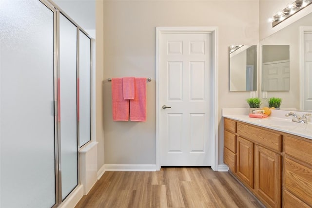 bathroom featuring baseboards, vanity, wood finished floors, and a shower stall