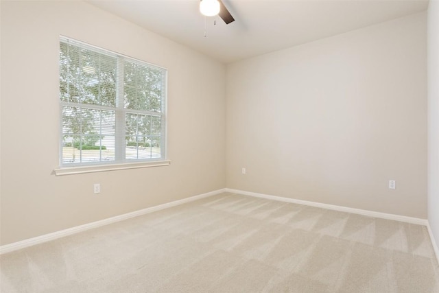 unfurnished room with a ceiling fan, light colored carpet, and baseboards