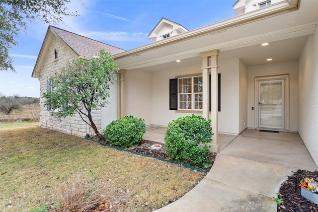 property entrance with a porch, a lawn, and stucco siding