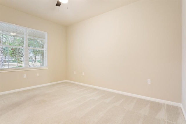 empty room featuring light colored carpet, baseboards, and ceiling fan