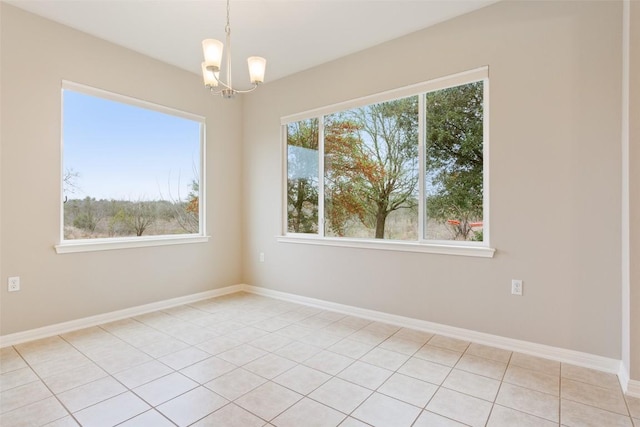 unfurnished room featuring plenty of natural light, baseboards, and an inviting chandelier