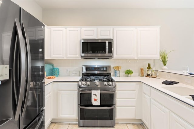 kitchen with white cabinetry, light countertops, light tile patterned floors, and stainless steel appliances