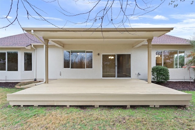 rear view of house with a deck, roof with shingles, and stucco siding