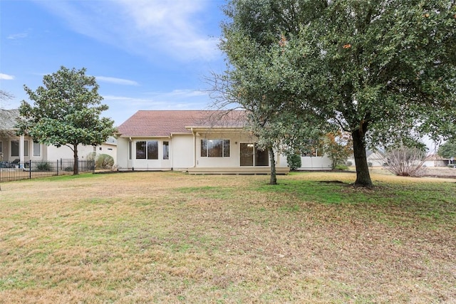 back of property featuring stucco siding, a lawn, and fence