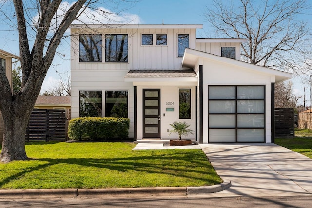 modern home featuring fence, driveway, an attached garage, a front lawn, and board and batten siding