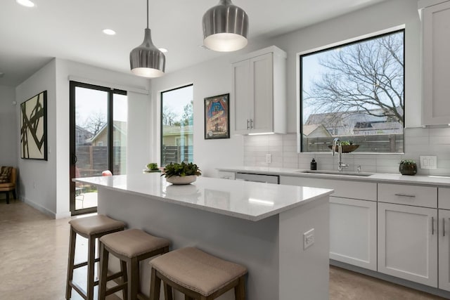 kitchen with a breakfast bar, pendant lighting, a sink, a kitchen island, and tasteful backsplash