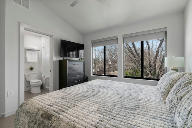 bedroom featuring multiple windows, lofted ceiling, visible vents, and ensuite bathroom