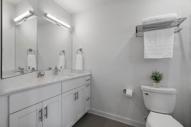 bathroom featuring baseboards, toilet, vanity, and tile patterned flooring