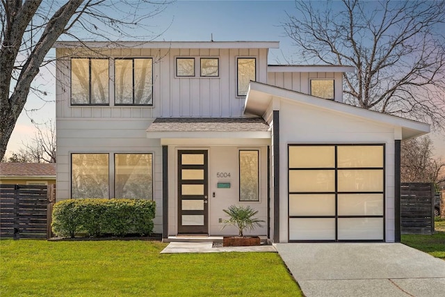 view of front of home featuring a front lawn, driveway, board and batten siding, a shingled roof, and a garage