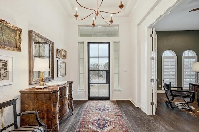 entryway featuring a chandelier, baseboards, dark wood finished floors, and crown molding