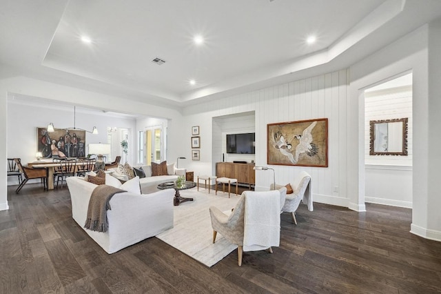 living room featuring dark wood finished floors, a raised ceiling, baseboards, and visible vents