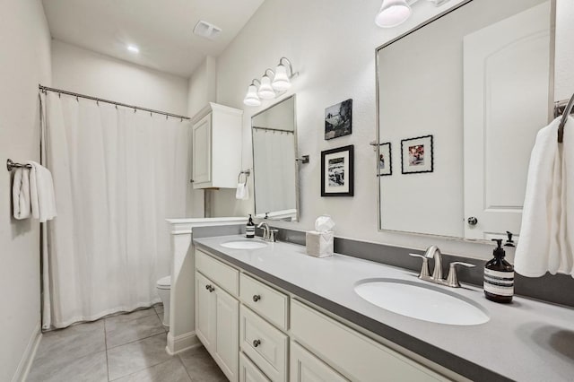 full bath with tile patterned floors, double vanity, toilet, and a sink