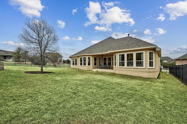 back of house with a yard, roof with shingles, a fenced backyard, and a patio area