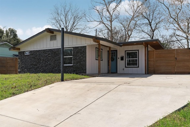 8516 Contour Dr, Austin, TX 78757 - view of front facade with fence, stone siding, board and batten siding, and concrete driveway