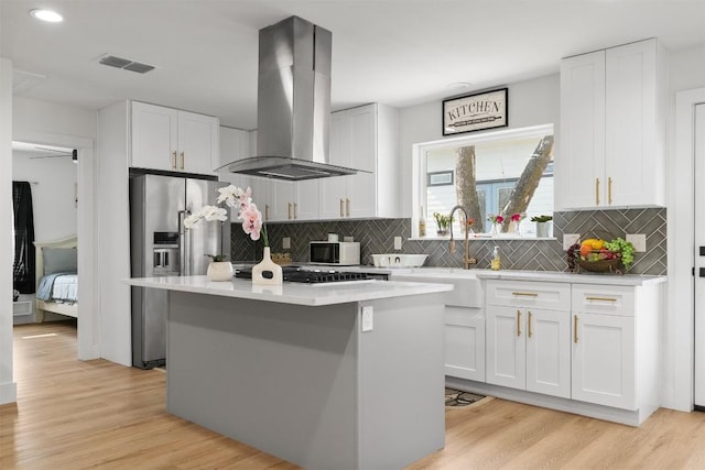 kitchen featuring visible vents, a center island, stainless steel appliances, light wood-style floors, and island range hood